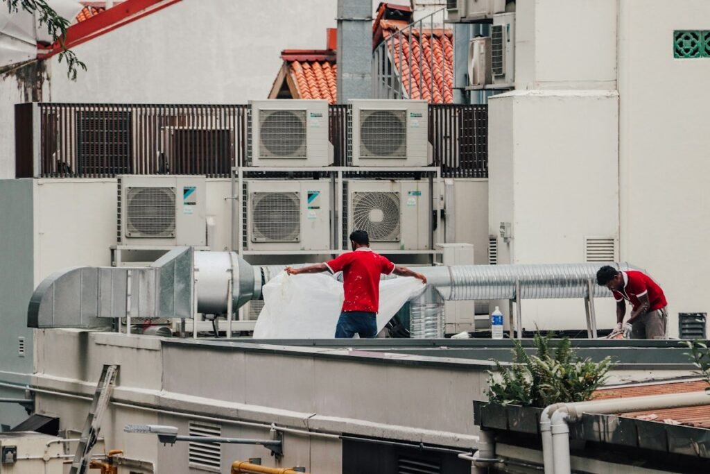 Two HVAC technicians working together on a rooftop